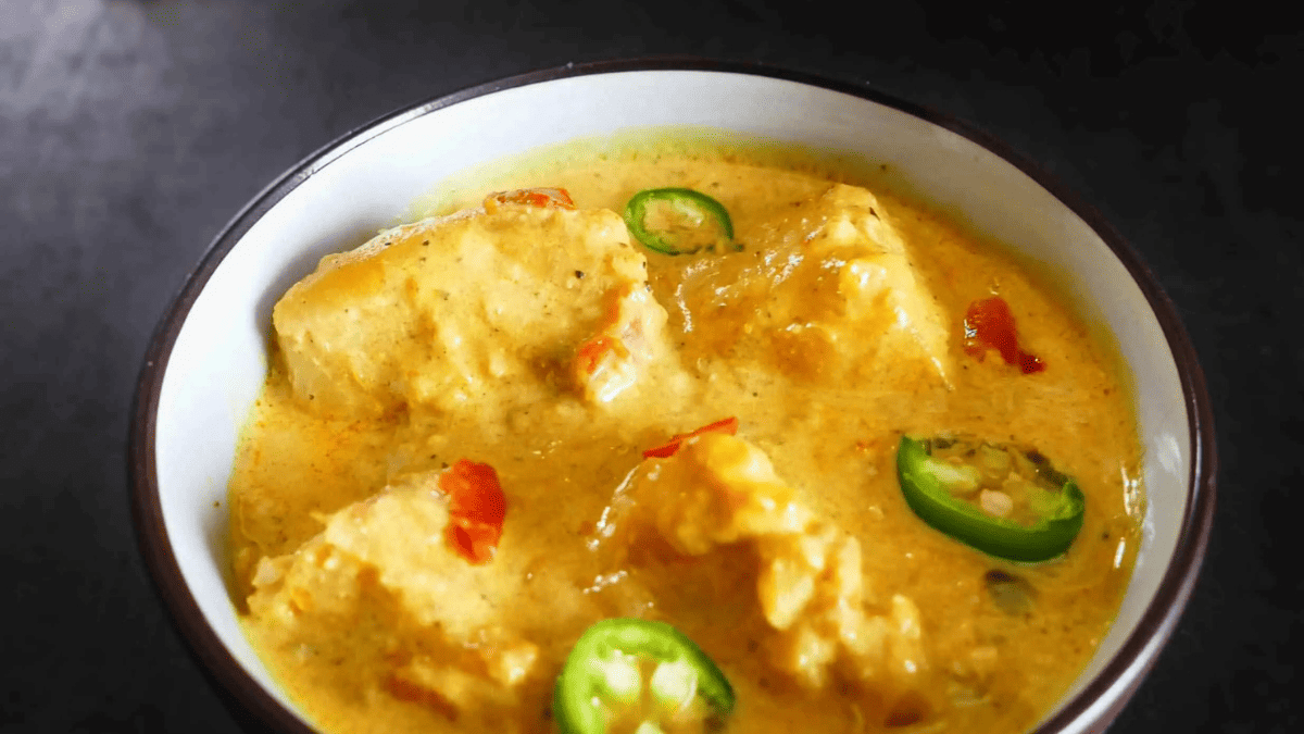 A bowl of fish curry with jalapeno slices on top.
