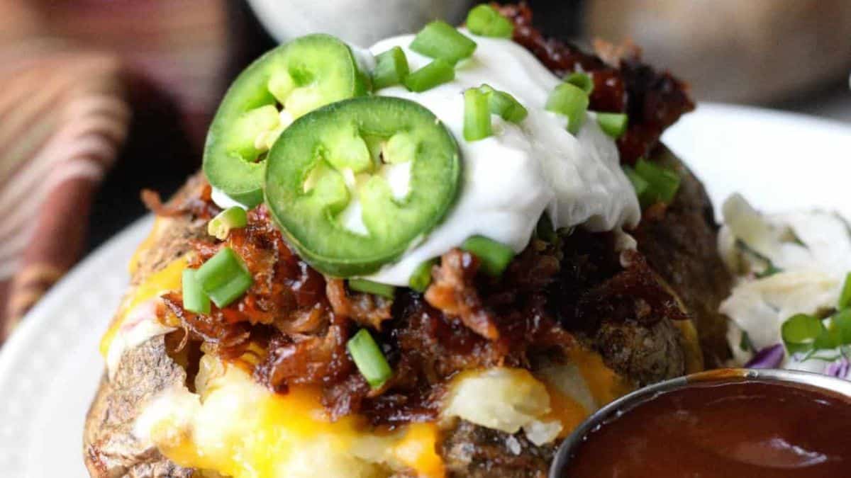 A baked potato loaded with pulled pork, sour cream and jalapenos.