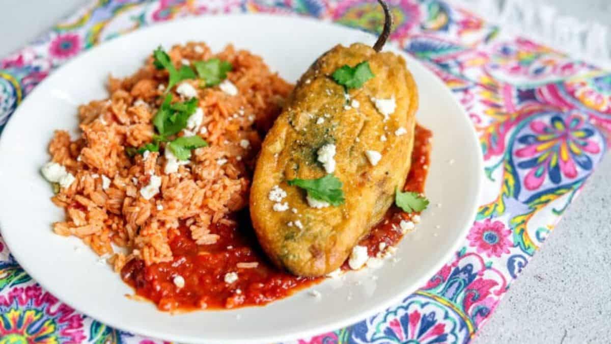 Chile Rellenos stuffed with smoked pulled pork on a plate with rice.