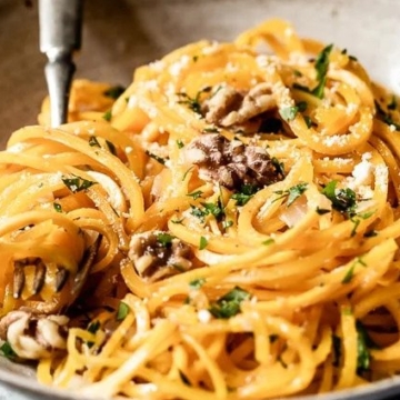 A bowl of spaghetti with walnuts and parmesan cheese.