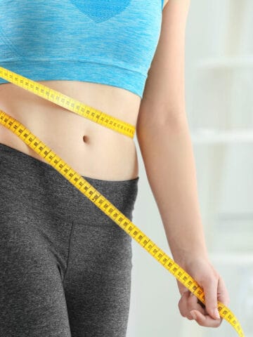 Young woman with measuring tape at home. Diet concept