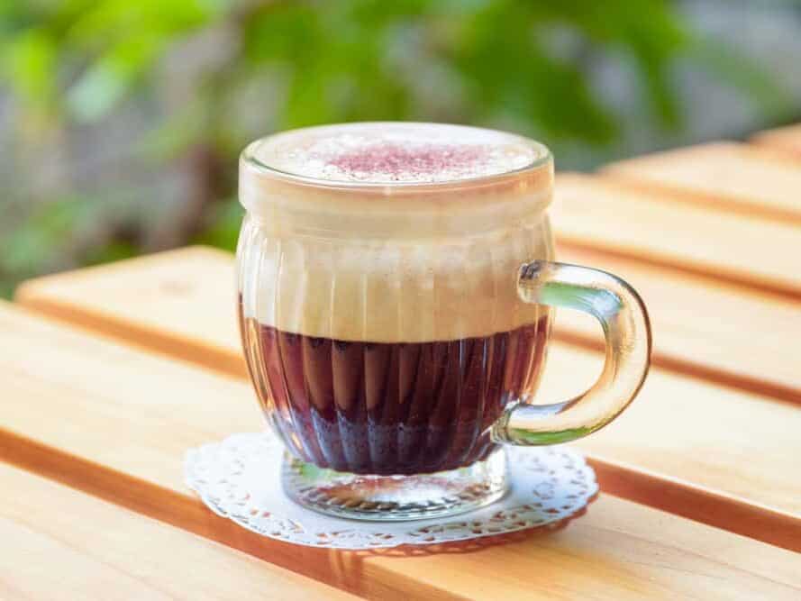 Cup of Vietnamese egg coffee (ca phe trung) on wooden table of street cafe on natural background. Traditional drink in Vietnam.