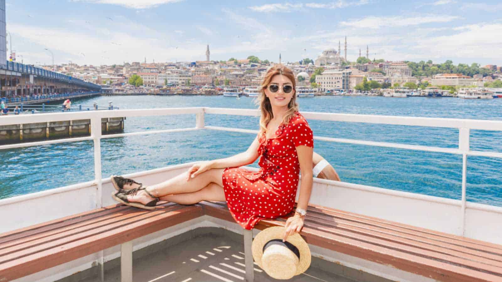 Beautiful woman cruises in ferry with view Galata bridge,Suleymaniye Mosque and Eminonu Town in Istanbul,Turkey
