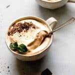 Two cups of coffee with whipped cream and chocolate, the perfect ending to a delicious meal.