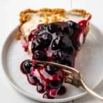 A slice of gluten-free blueberry pie on a plate with a fork.