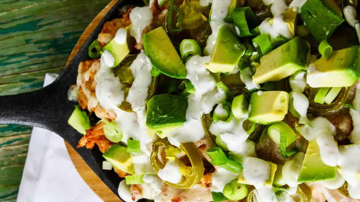 A skillet of tater tot nachos topped with pork.