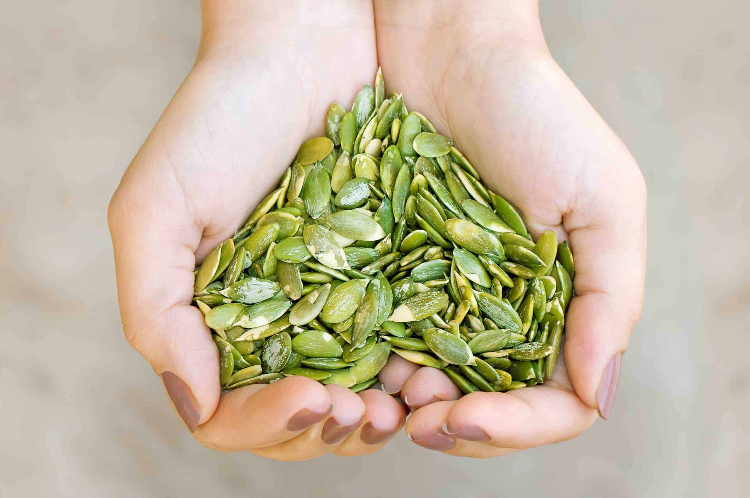 Pumpkin seeds' kernel in woman hands forming heart shape