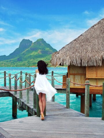 Young lady stand alone , look towards to the Otemanu mountain at Bora Bora island , French Polynesia , Pacific ocean .