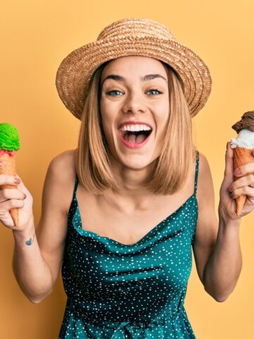 Young caucasian blonde woman eating ice cream cone smiling and