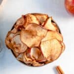 Apple chips in a bowl with cinnamon sticks make for a delicious and healthy snack option.