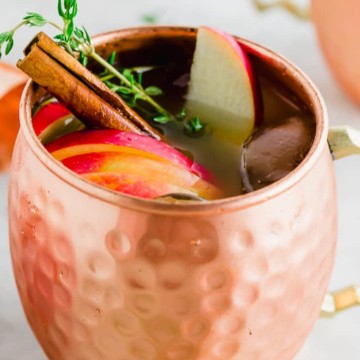 Thanksgiving Cocktail Recipes: Two copper mugs with apples and cinnamon.