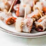 Gluten Free bacon wrapped dates on a plate with toothpicks.