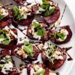 46 Roasted beets with goat cheese and balsamic vinaigrette on a white plate.