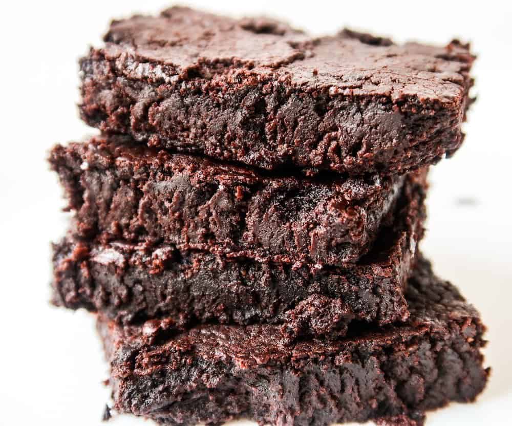 A stack of gluten-free chocolate brownies on a white plate.