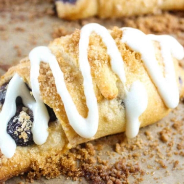 Blueberry crescents with icing made with flaky crescent rolls are baked to perfection on a baking sheet.