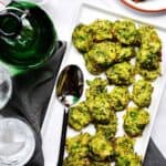 A gluten-free appetizer consisting of broccoli florets served on a white plate, accompanied by a refreshing glass of water.