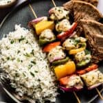 50 Easy Gluten Free Dinners featuring Kebab skewers on a plate with rice and tzatziki sauce.