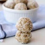 A stack of coconut energy balls, a healthy snack recipe, on a white plate.