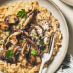 Two plates of gluten-free risotto with mushrooms and parsley.