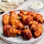 30 delicious chicken wings on a plate with a mouthwatering dipping sauce.