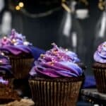 A group of Gluten Free cupcakes with purple frosting on a dark background.