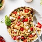 A gluten-free bowl of pasta salad with tomatoes and basil.