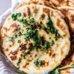 Naan bread with herbs on a white cloth, perfect for gluten-free appetizers.