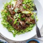 A bowl of gluten-free beef and broccoli with sesame seeds.