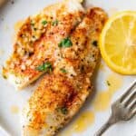 50 Easy Gluten Free Dinners featuring fish fillets on a white plate with lemon slices.