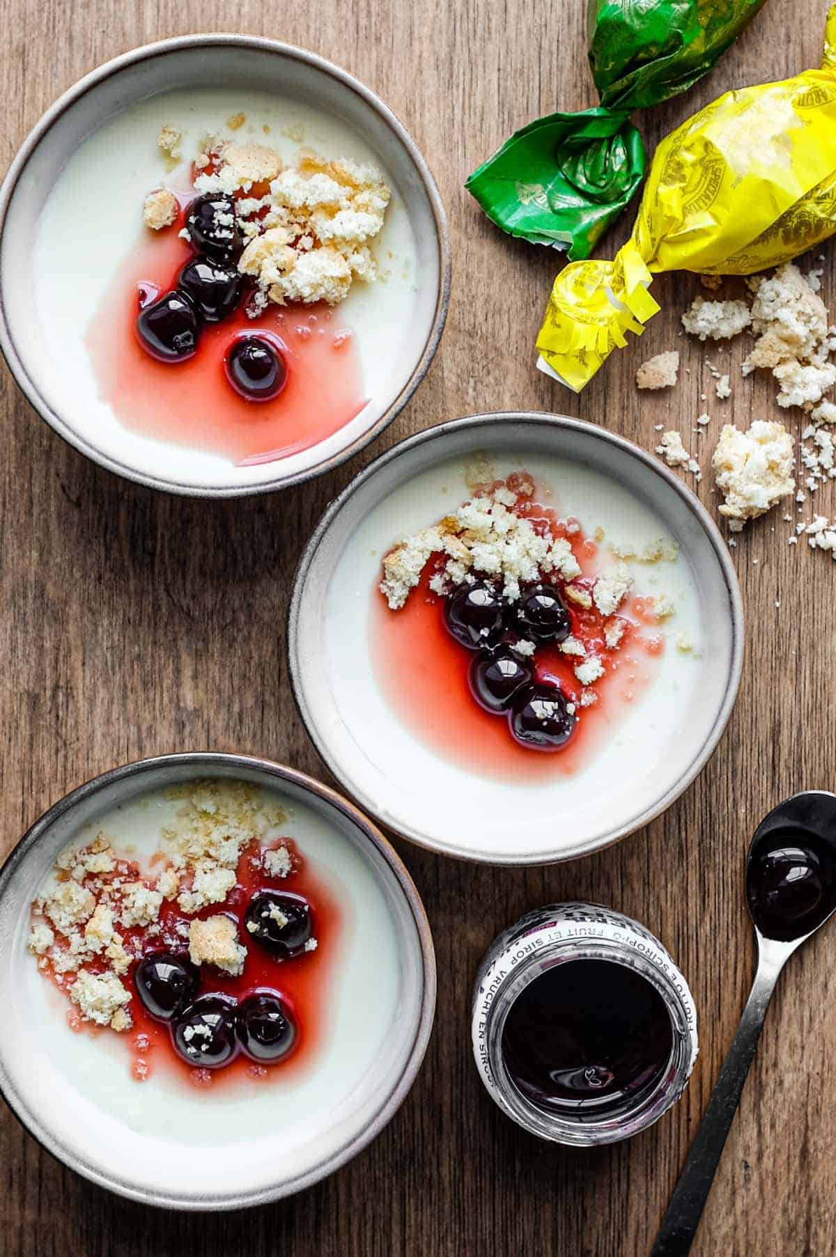 Three bowls of gluten-free yogurt with blueberries and granola on a wooden table.