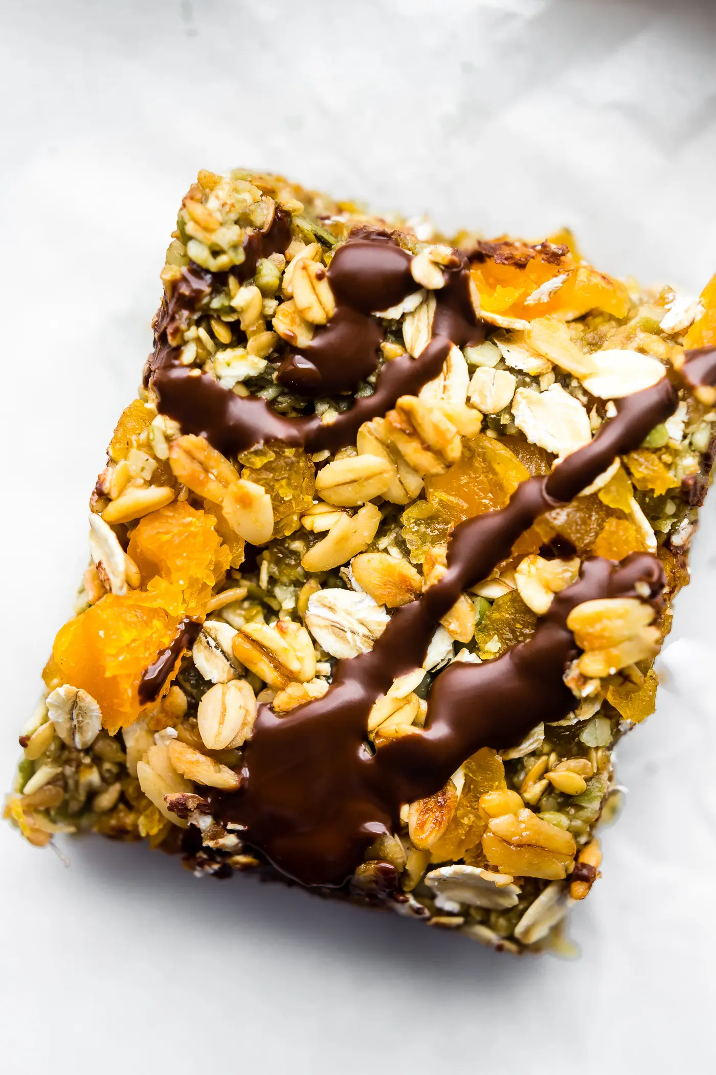 A piece of granola bar with chocolate drizzle.