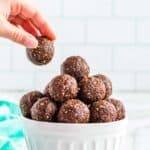 A hand reaching into a bowl of healthy chocolate energy balls.