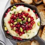 A bowl of gluten-free pomegranate hummus with toasted bread.