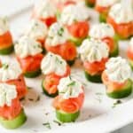 Enjoy 46 gluten-free smoked salmon and cucumber appetizers on a white plate.