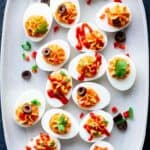 46 Deviled eggs on a plate with ketchup and olives.