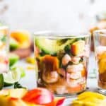 Three glasses with 46 gluten-free appetizers, including shrimp and mangoes.