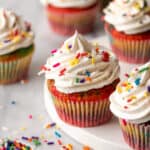 Gluten free rainbow cupcakes with whipped cream and sprinkles.
