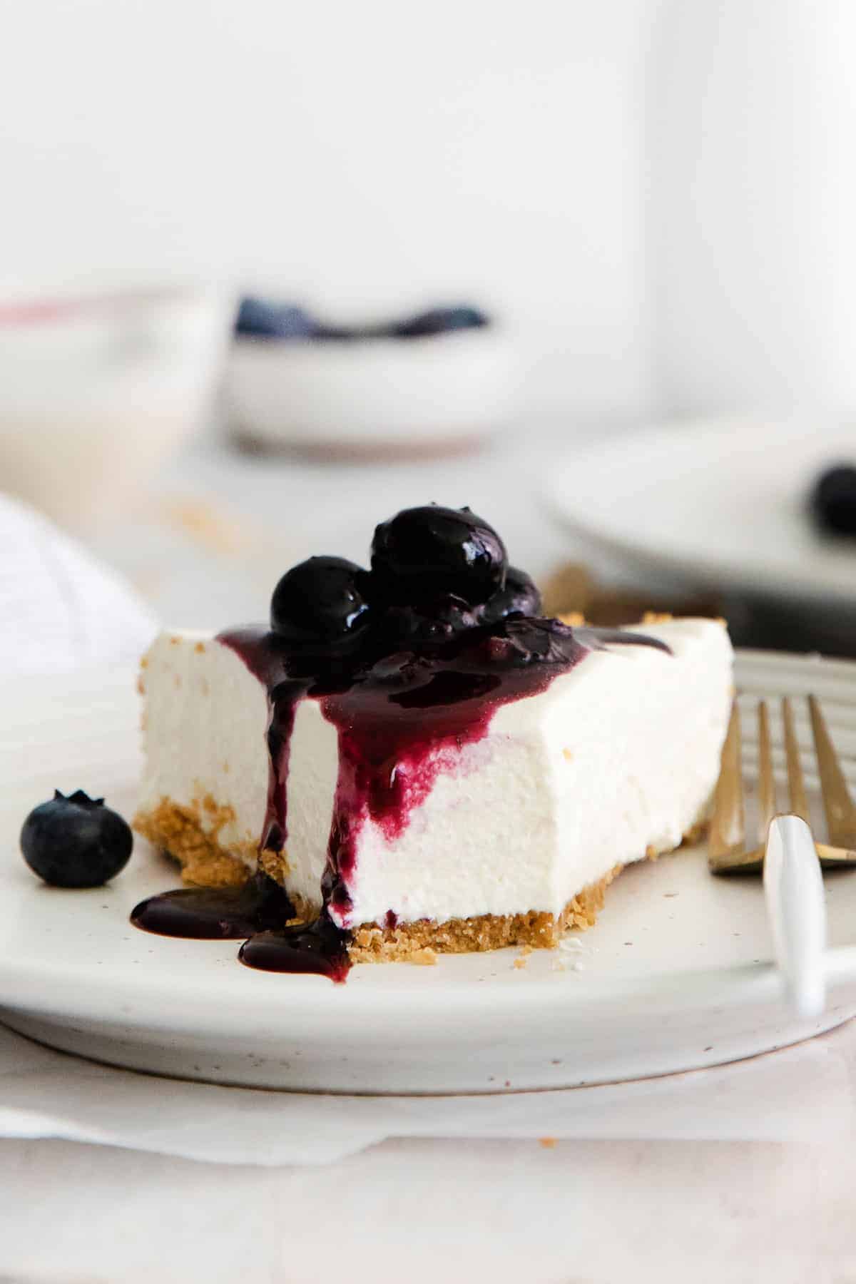 A slice of gluten-free blueberry cheesecake on a white plate.