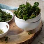 Healthy kale chips on a wooden cutting board.