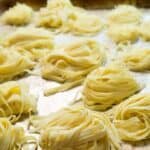 Gluten-free pasta strands on a baking sheet.