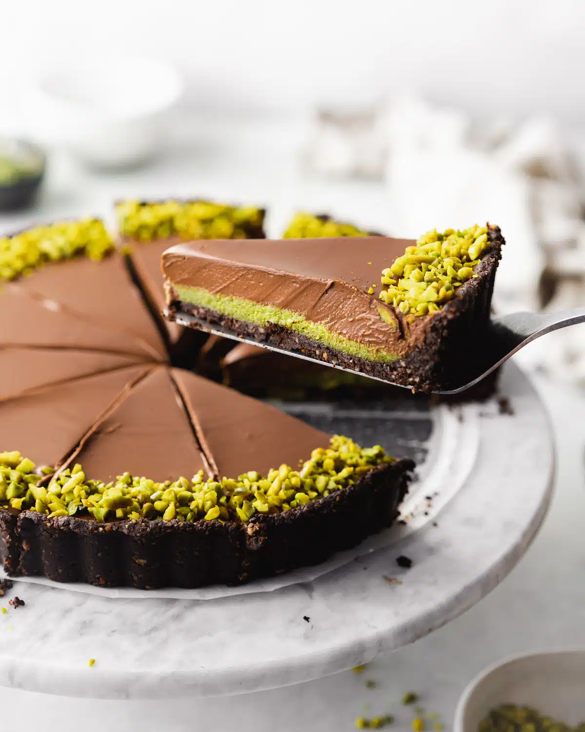 An easy-to-make chocolate pistachio tart with a slice taken out, perfect for gluten-free dessert lovers.