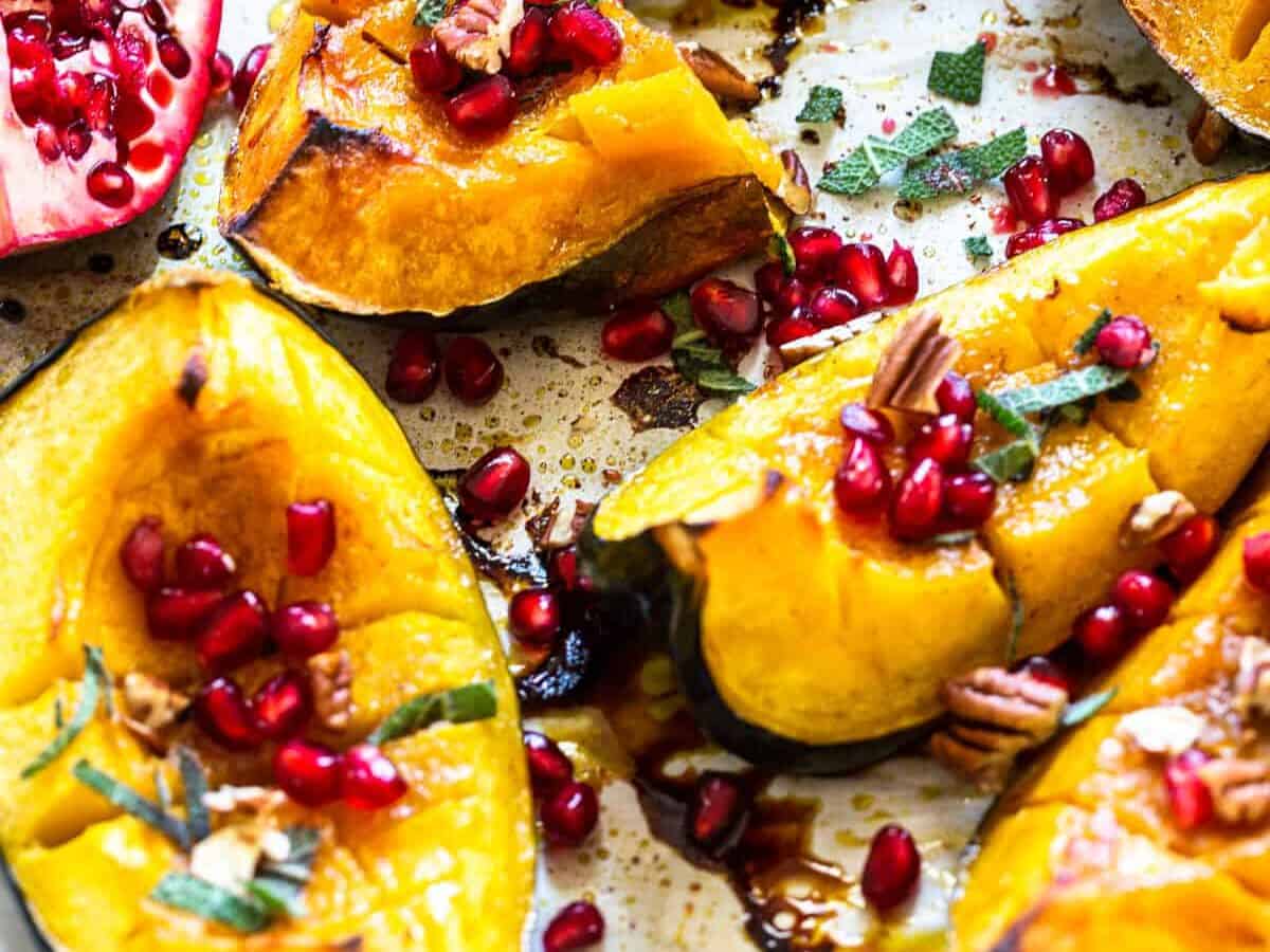 Roasted squash on a sheet pan with pomegranate seeds.