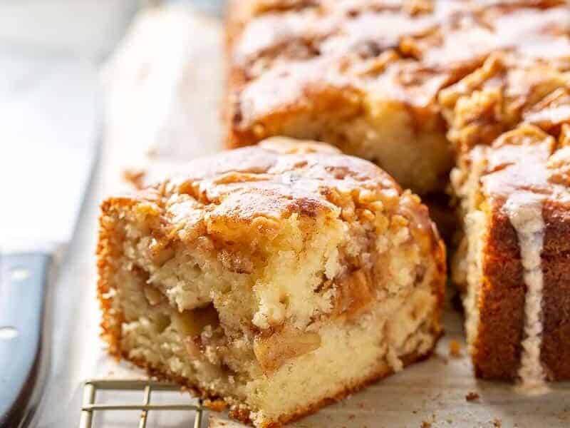 Apple cake with slice out on a cooling rack.