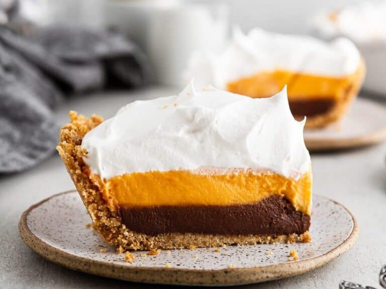 Slice of sweet potato pie with whipped cream on a brown plate.