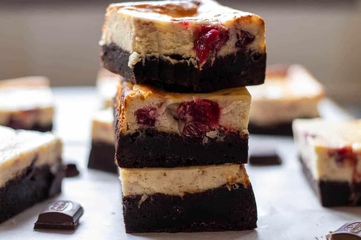Cheesecake brownies stacked up high with bite out.