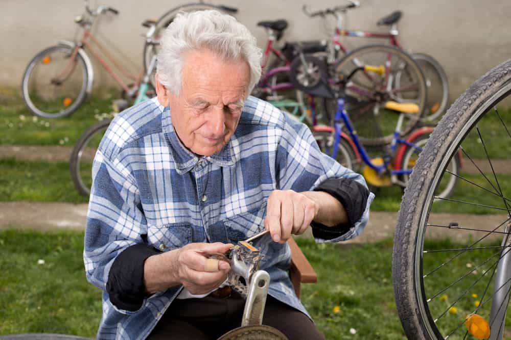 Bicycle mechanic repairing bicycle pedal in courtyard