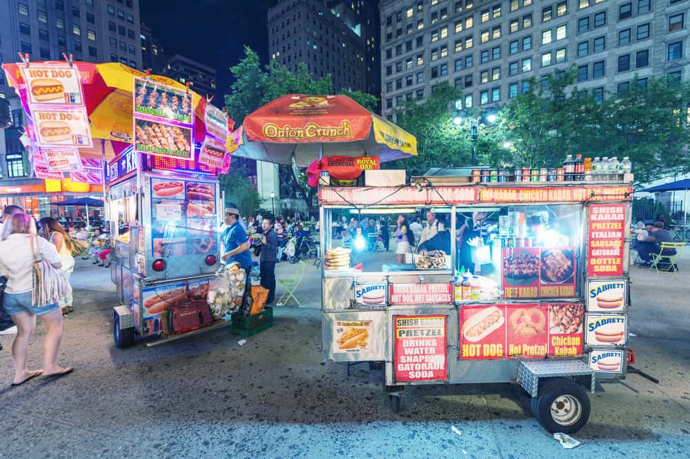NEW YORK CITY - JUNE 12, 2013: New York street seller in a Manhattan square at night. Food sellers are all over Manhattan offering a variety of street foods.