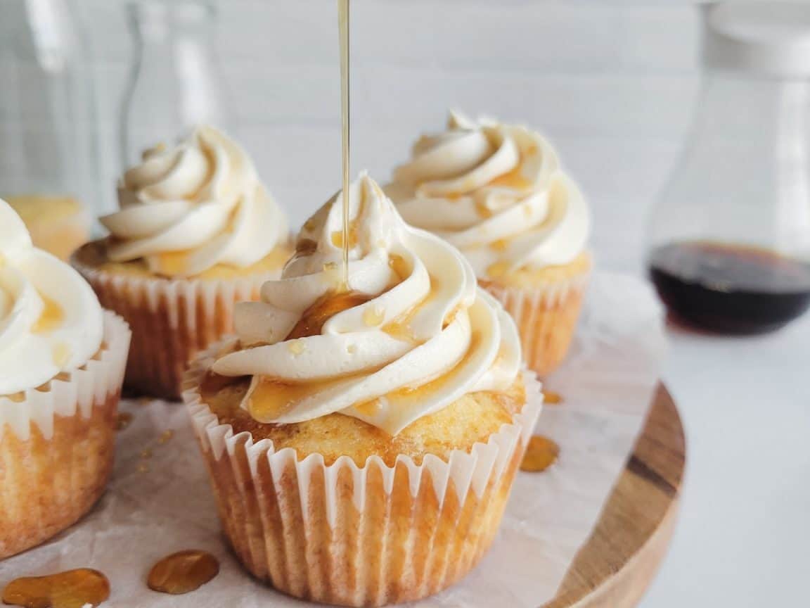 Maple cupcake with syrup being poured on.