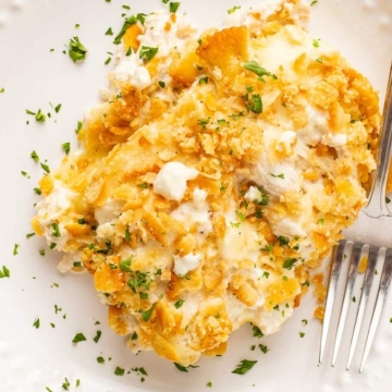 A delectable cheesy chicken casserole, served temptingly on a white plate with a fork.