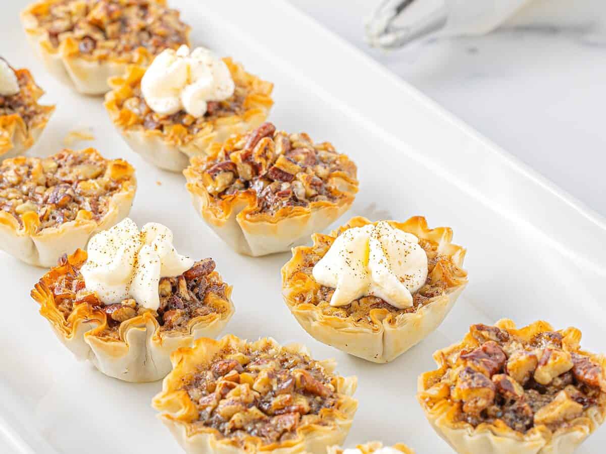 Mini pecan pies on white tray.